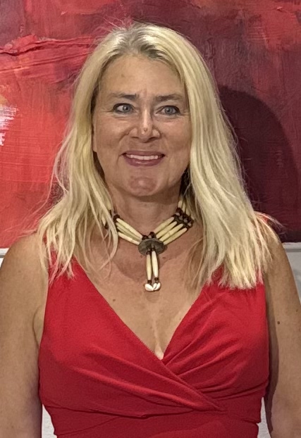 Porträt von Susanne Rikus vor einem roten abstrakten Gemälde, mit blondem Haar und rotem Kleid